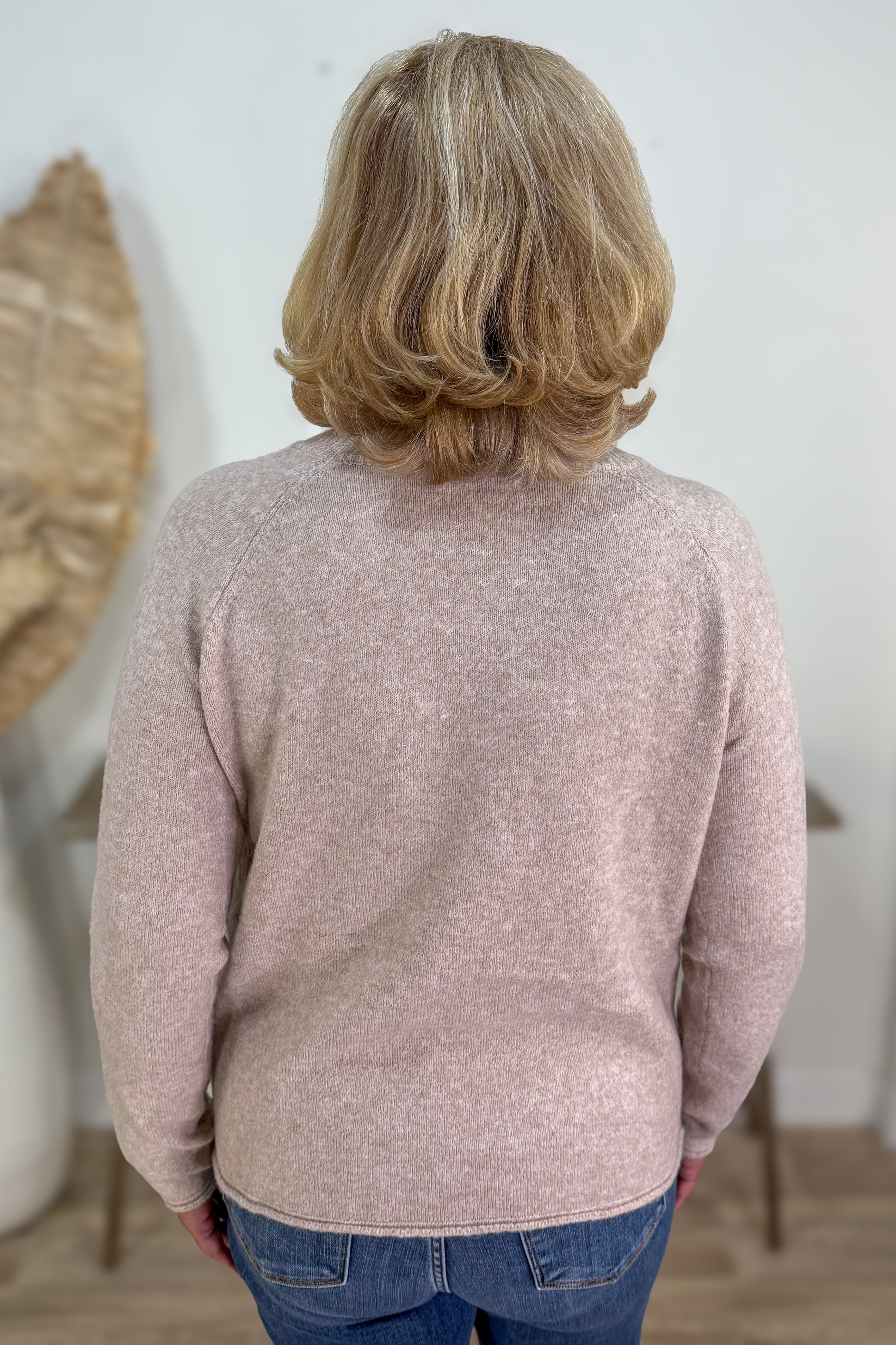 Person wearing a pink sweater in a minimal indoor setting