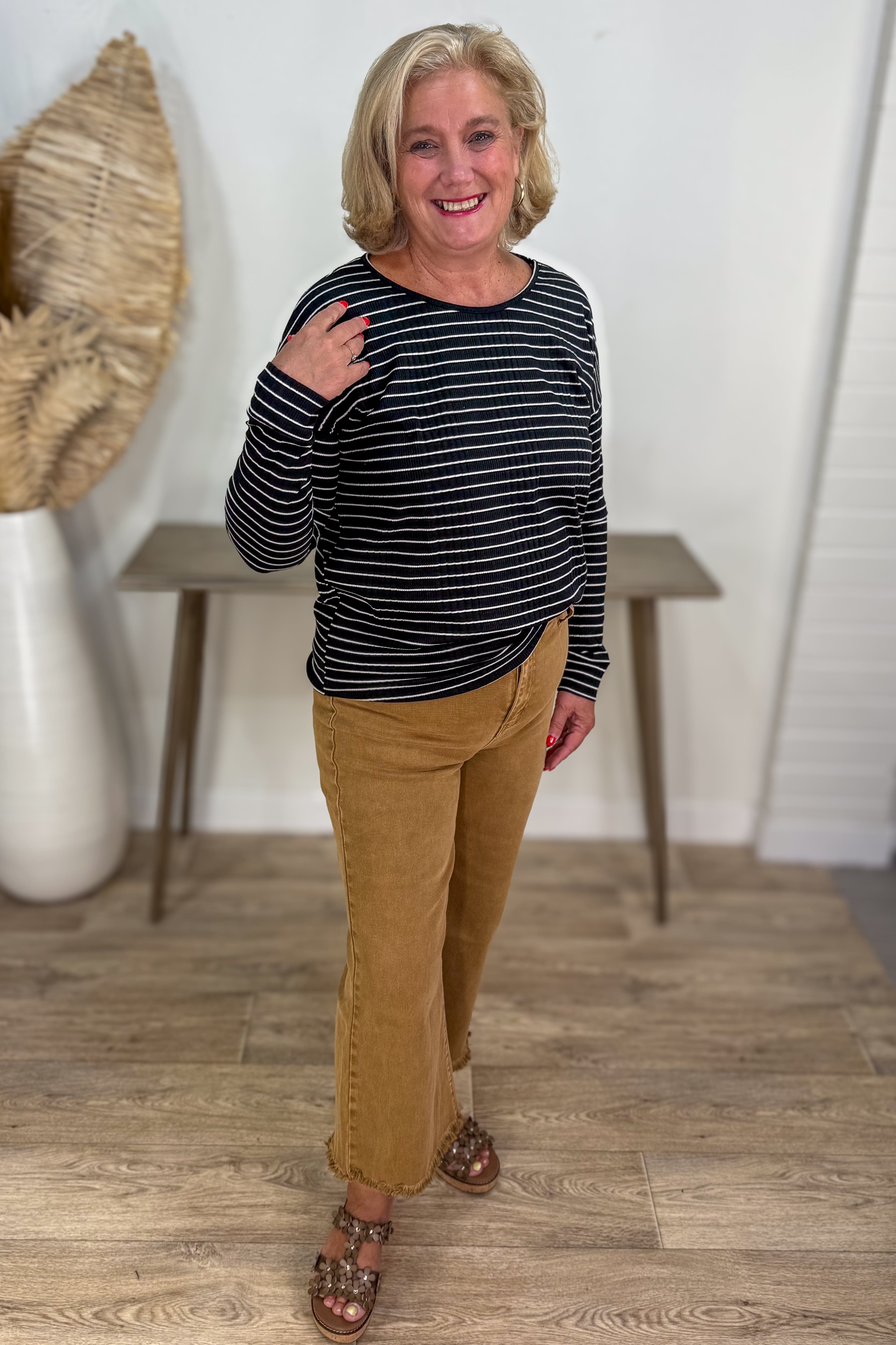 Woman wearing a striped shirt and tan pants indoors.