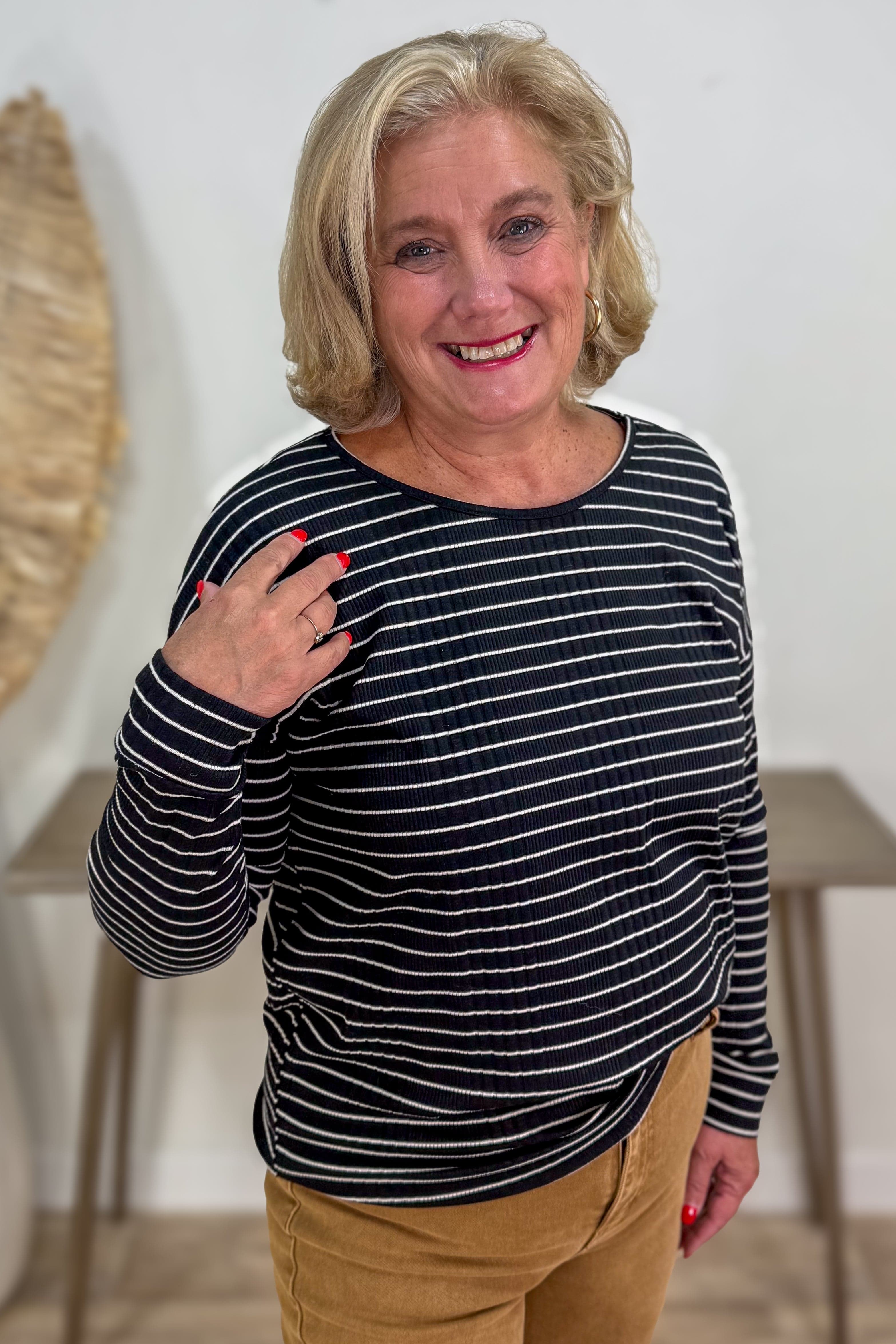 Woman wearing a black and white striped shirt with beige pants indoors.