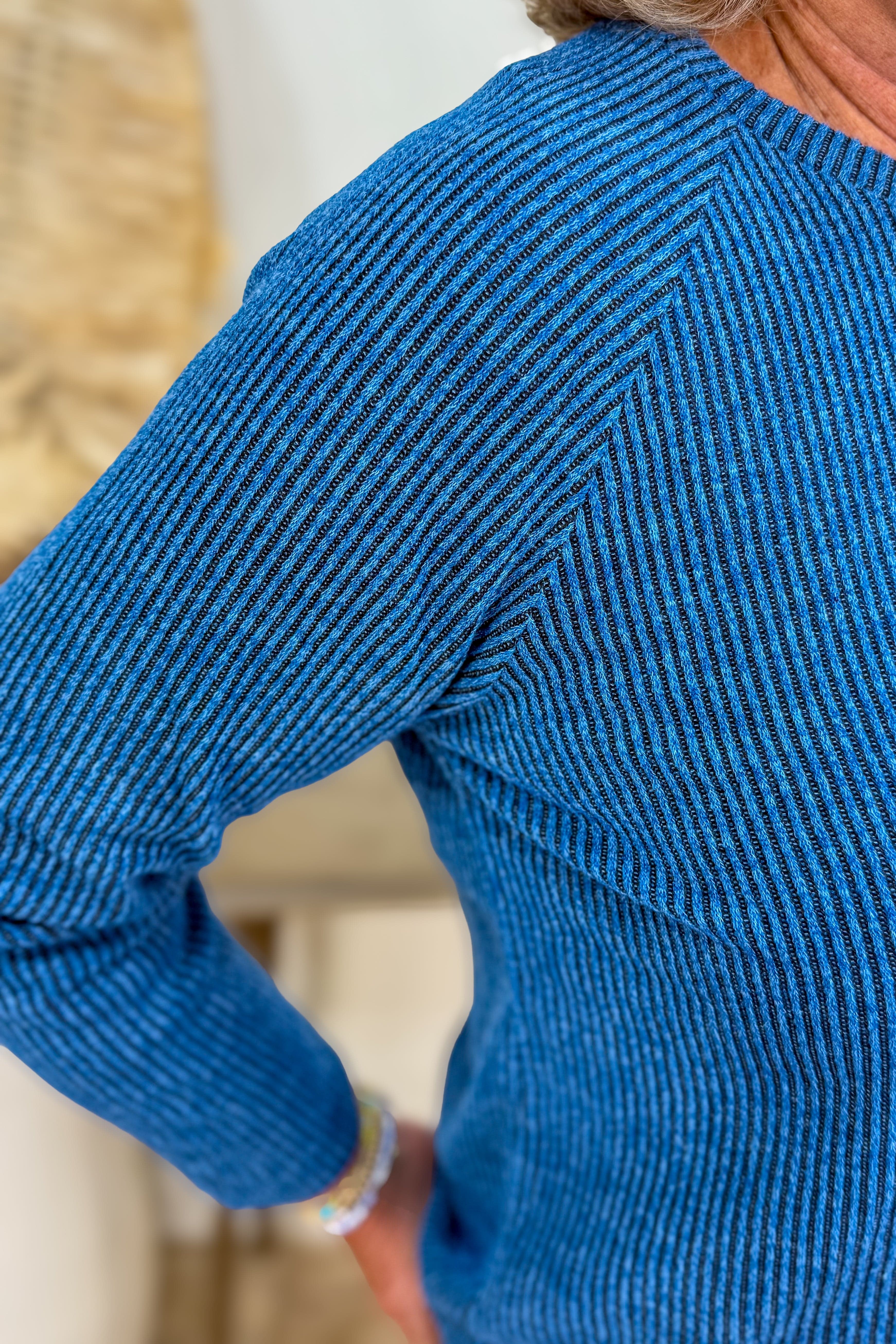 Person wearing a blue sweater with a blurred background