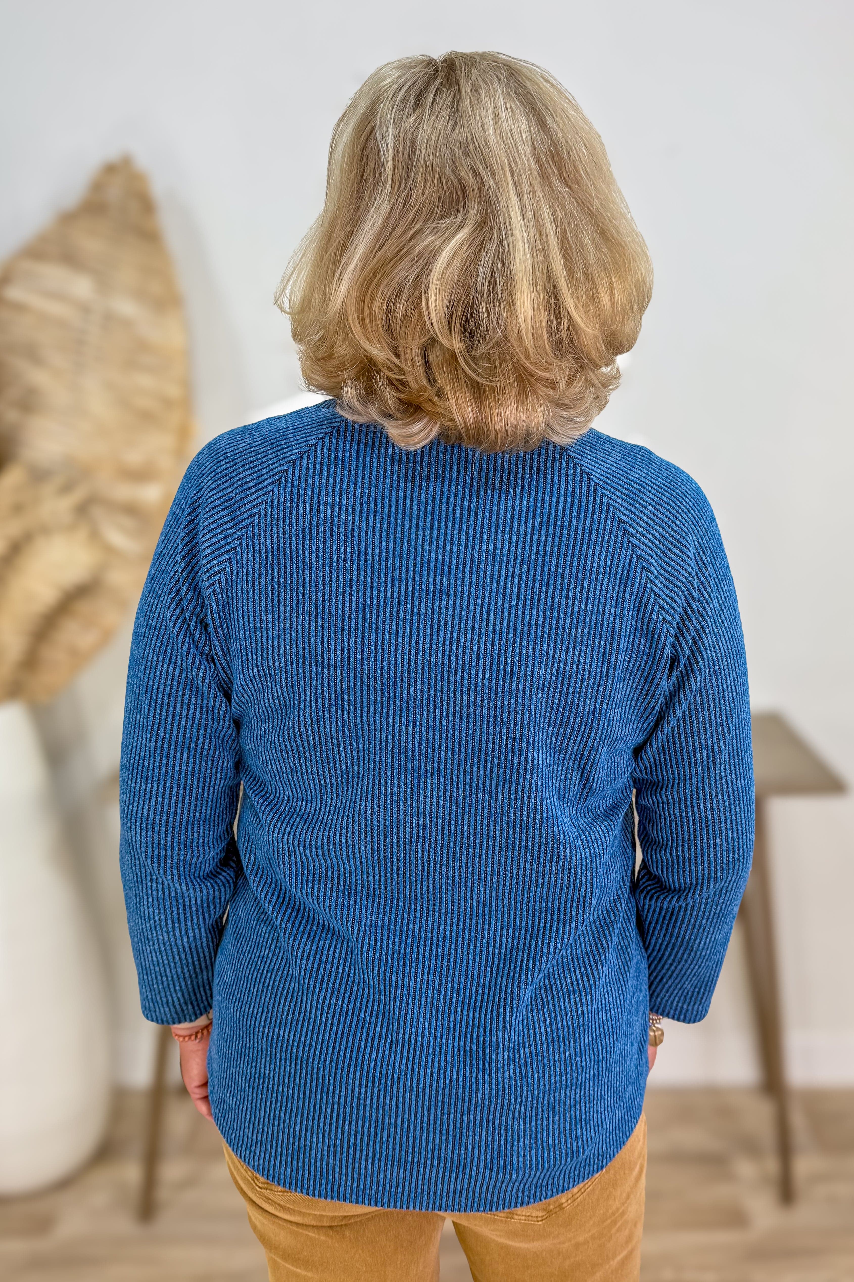 Person wearing a blue textured sweater in an indoor setting
