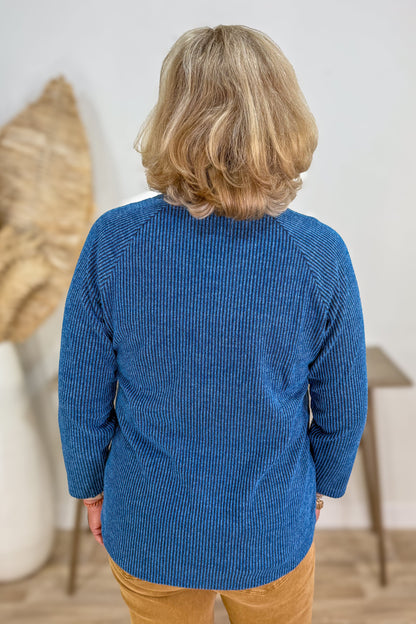 Person wearing a blue textured sweater in an indoor setting