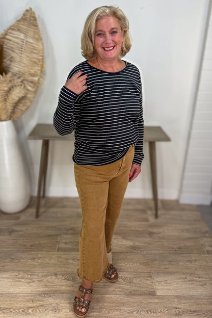 Woman wearing a striped shirt and tan pants indoors.