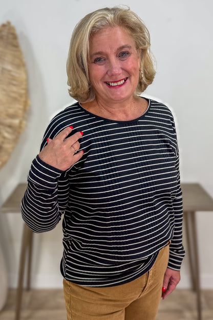 Woman wearing a black and white striped shirt with beige pants indoors.