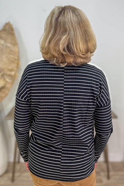 Person wearing a black and white striped shirt with a neutral background