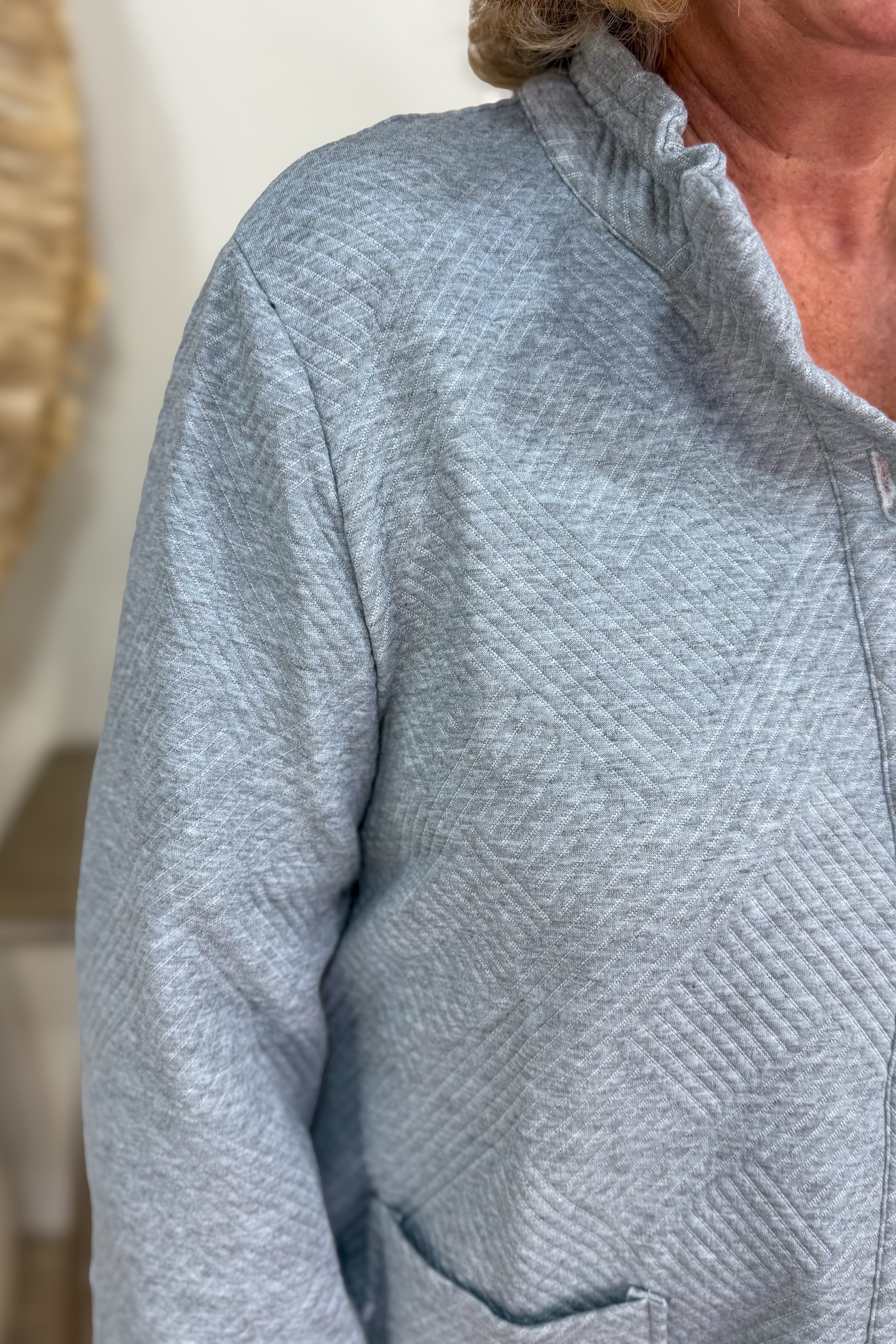 Close-up of a person wearing a textured gray jacket with a blurred background
