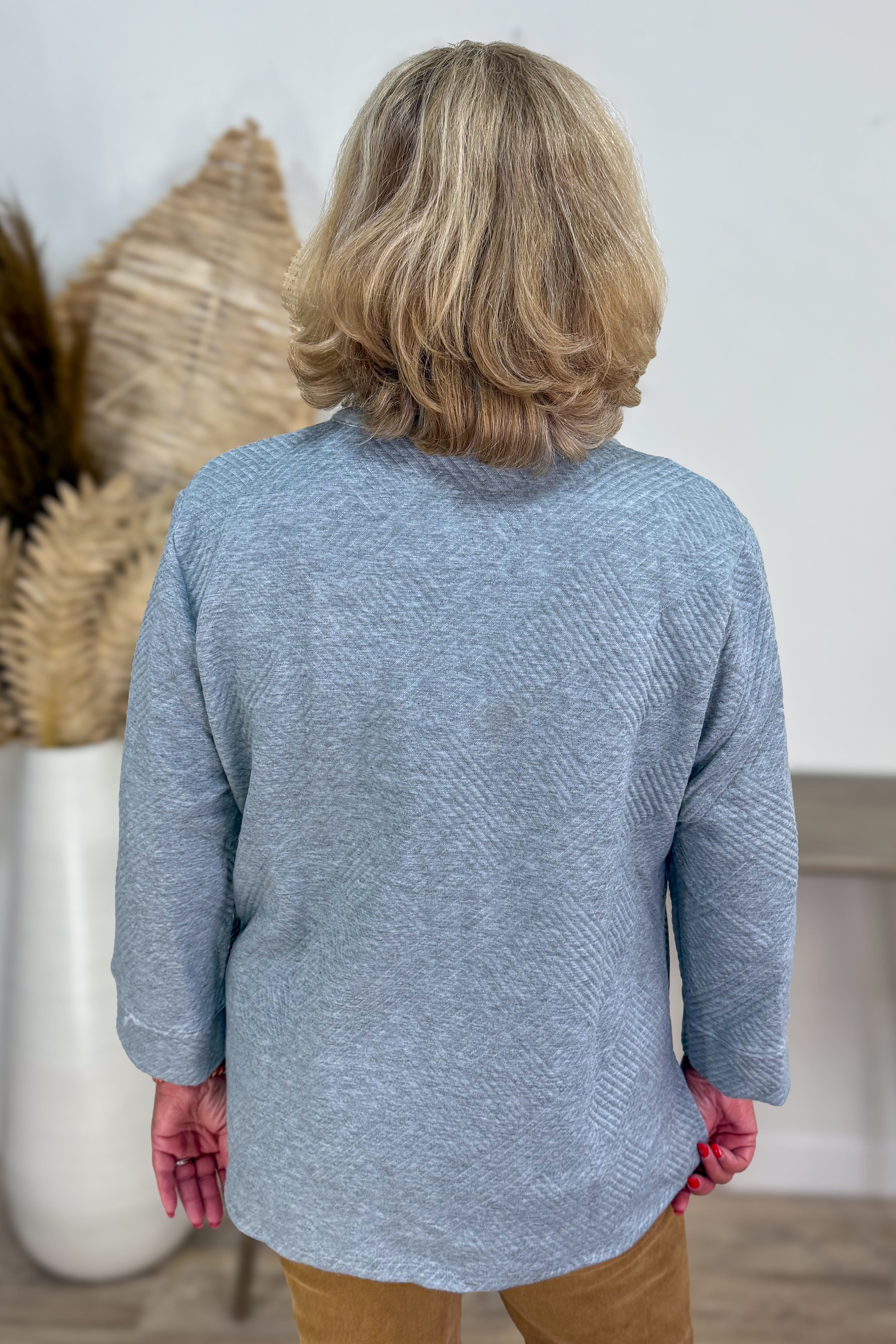 Person wearing a blue sweater with a neutral background