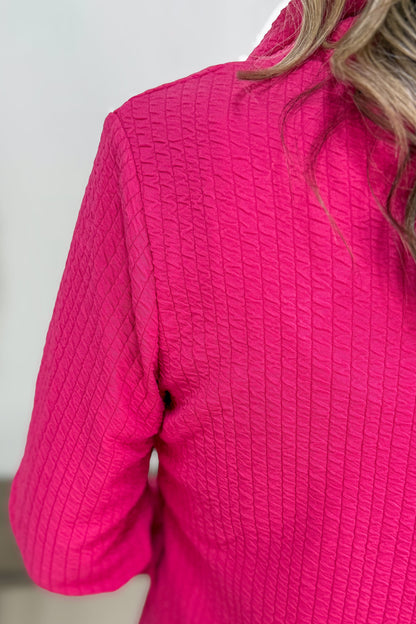Close-up of a bright pink textured jacket worn by a person.