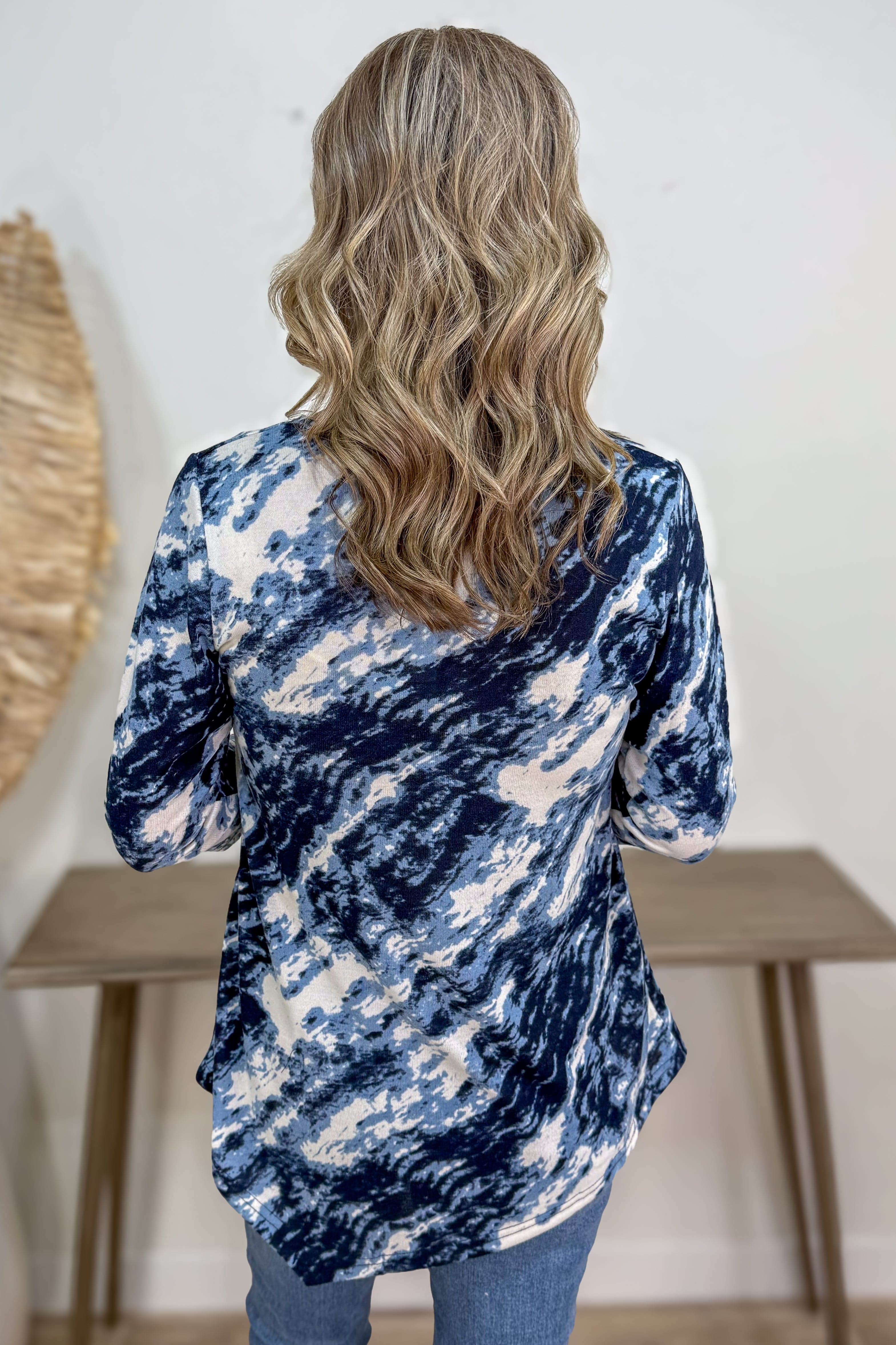 Person wearing a blue and white tie-dye shirt with a neutral background