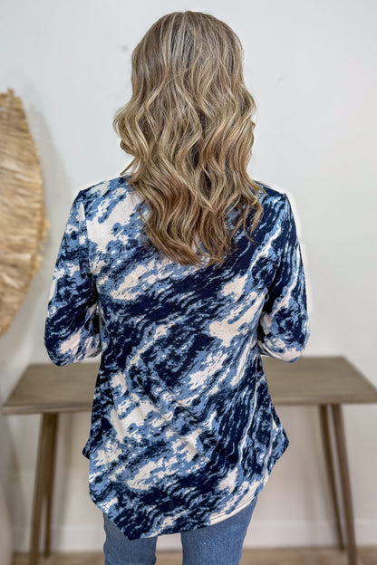 Person wearing a blue and white tie-dye shirt with a neutral background