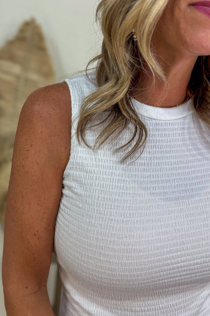 Woman wearing a white sleeveless top with a blurred background